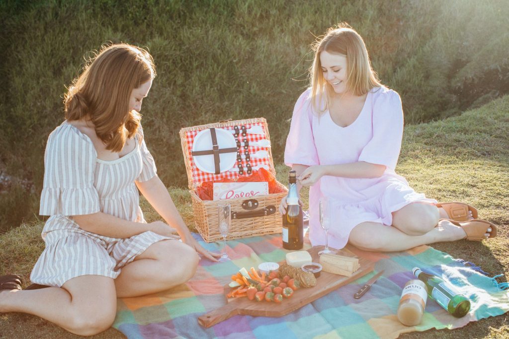 Two young women enjoy a picnic at sunset