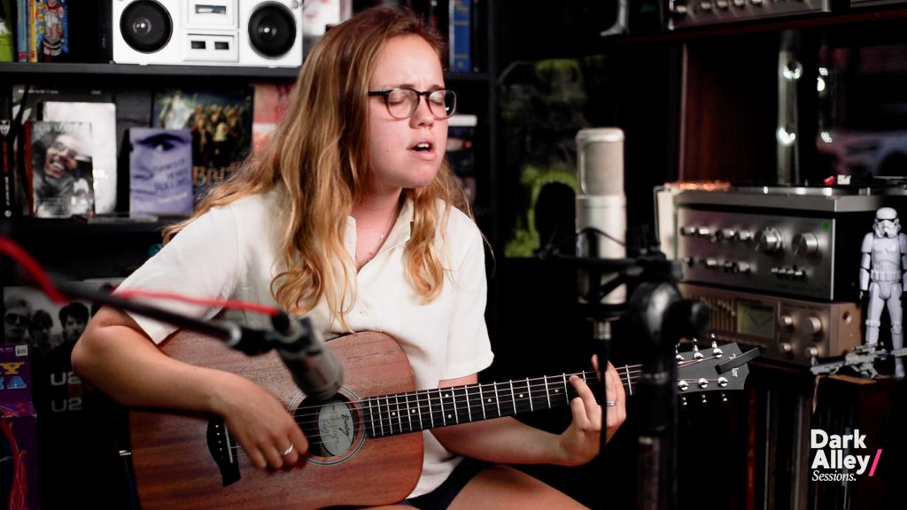 A young woman playing the guitar in a record store