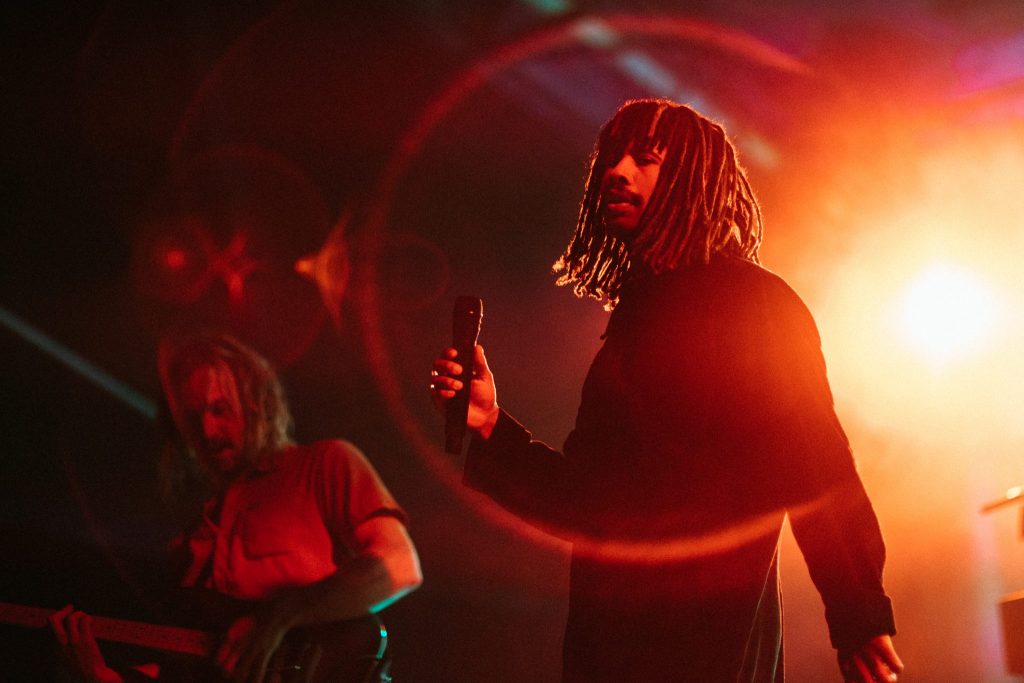 A singer and guitarist under coloured lights