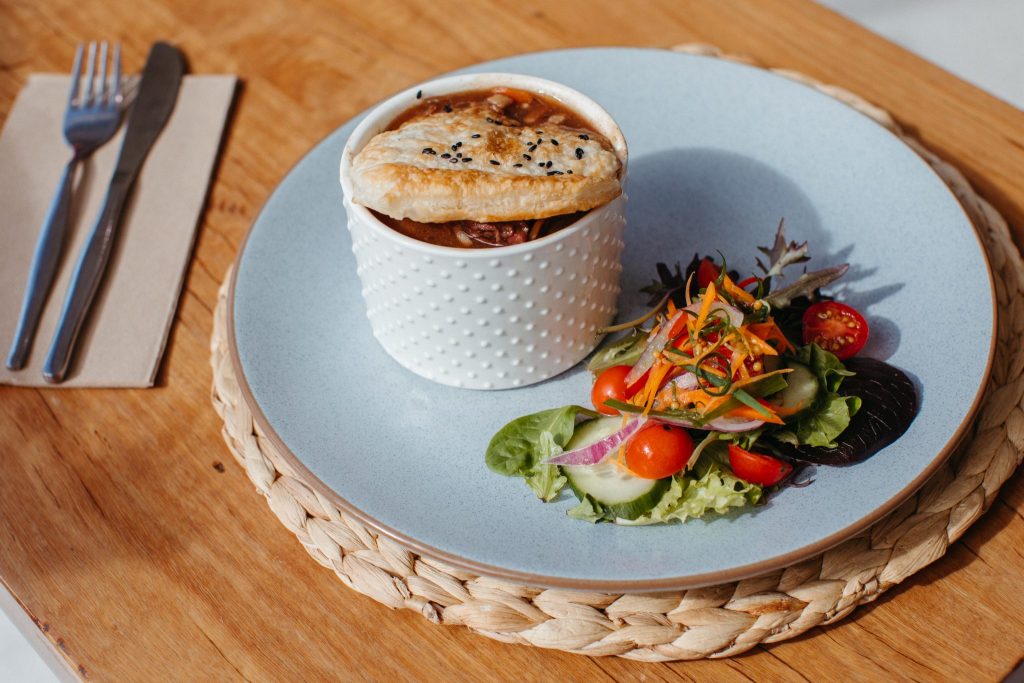 Pot pie on a light blue plate with a side salad