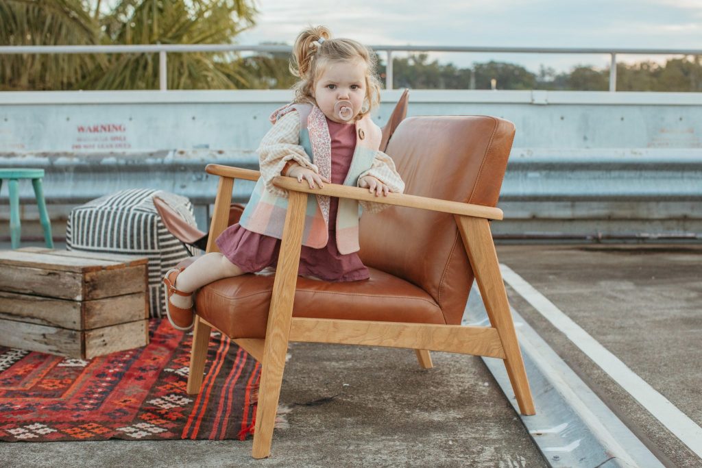 A toddler kneeling on an arm chair 