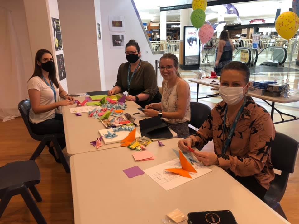 Four women fold origami butterflies