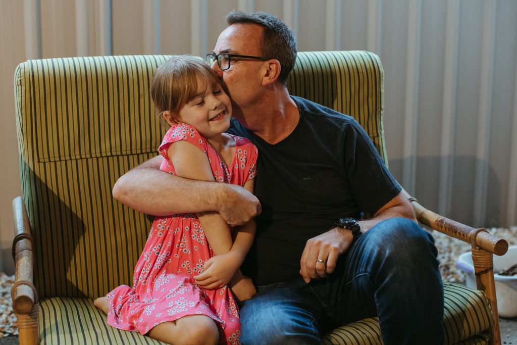 A dad kisses his young daughter on the cheek