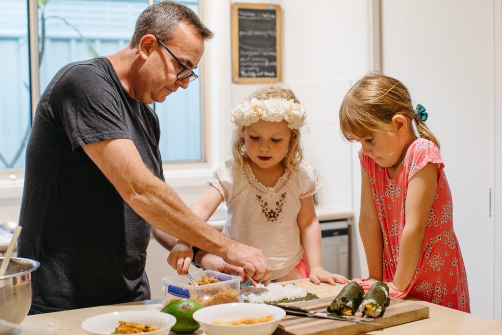 A dad and two little girls make sushi 