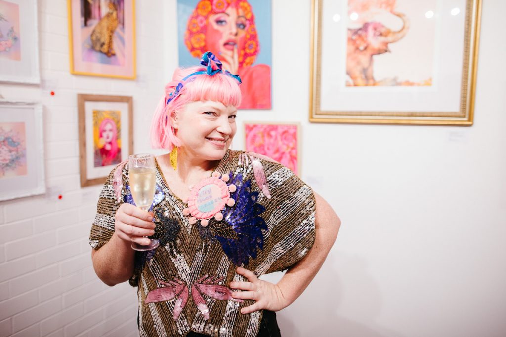 A woman with pink hair strands in front of art works
