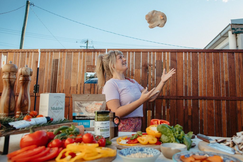 A woman tossing pizza dough 
