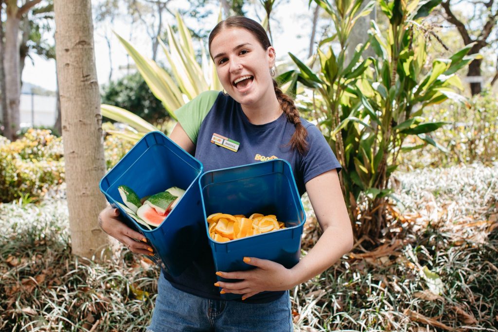 A young woman holds fruit scraps to put in the Coffs Central compost
