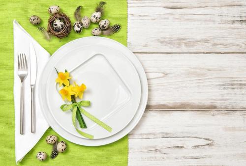 Easter table decoration eggs and narcissus flowers with green table runner. 